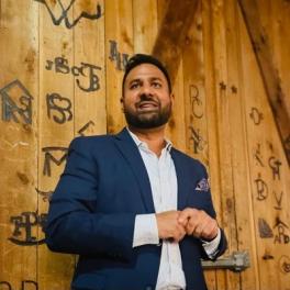 Vijay Agarwal standing in front of a brown wall smiling